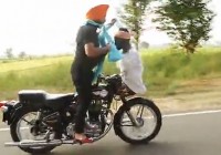 Motorcyclist ties a turban while driving with