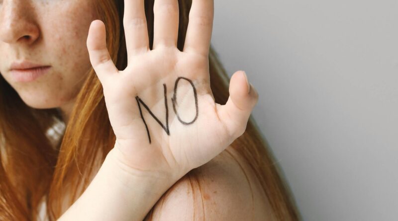 Woman making a 'no' gesture with her hand, representing boundary-setting and self-respect